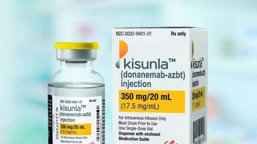 Foto da embalagem e do frasco de vidro do remédio Kisunla. As cores branco e amarelo estão presentes nas embalagens.