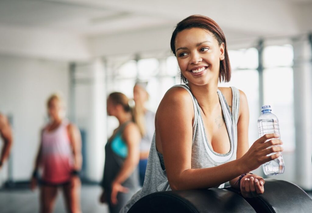 mulher em um ambiente de ginastica e bebendo água