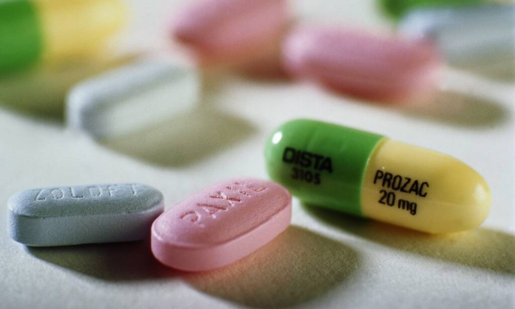 Cápsulas de remédio jogadas em cima de uma mesa. Uma delas é de Prozac,um dos primeiros antidepressivos a usar a fluoxetina como princípio ativo.