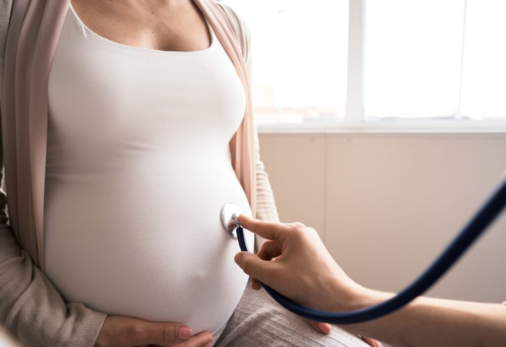 Mulher gravida sendo examinada com um estetoscópio pelo médico