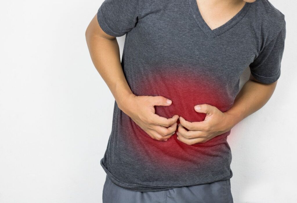 homem com as mãos na barriga indicando que está com dores abdominais