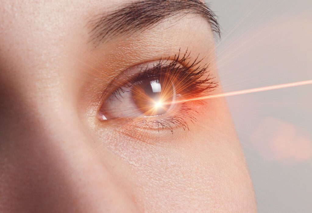 Olho de uma mulher recebendo um laser laranja.