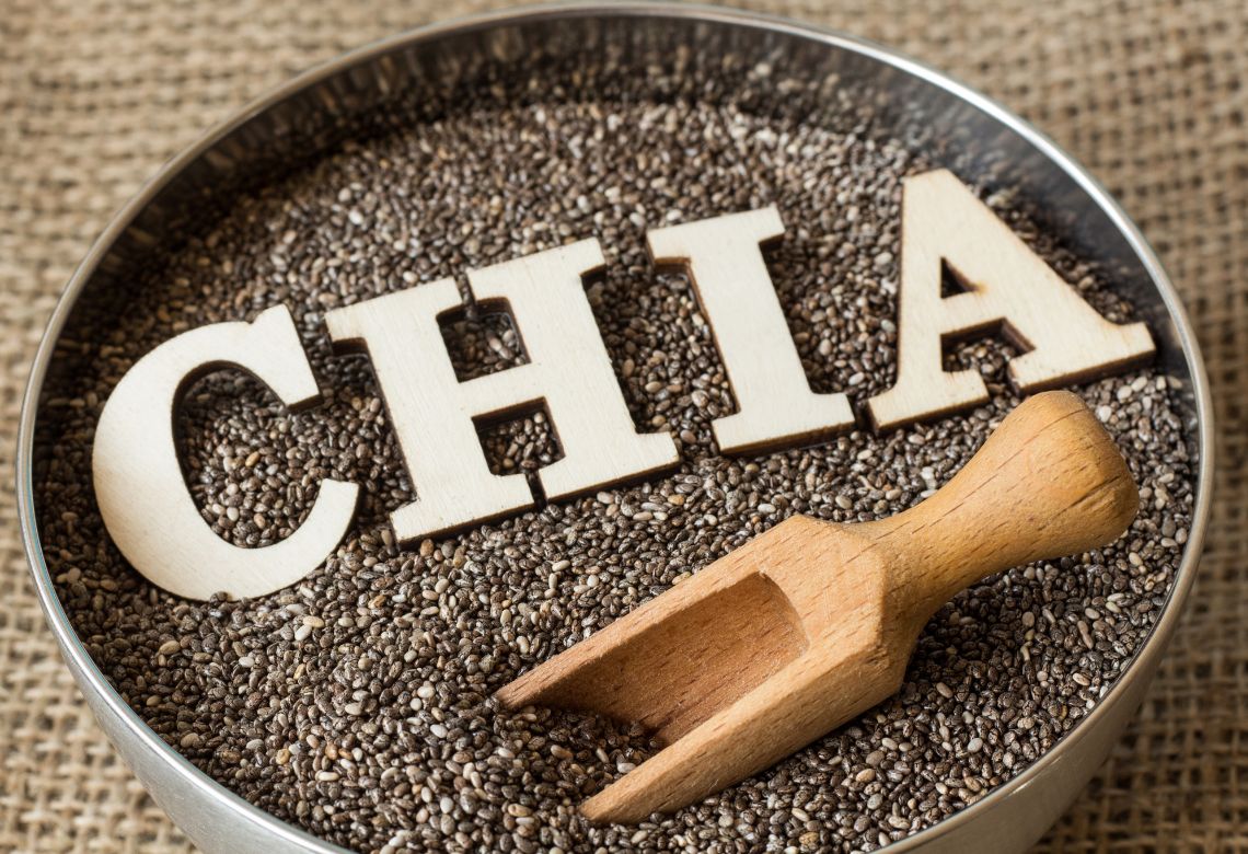 pote marrom com sementes de chia, com letras ao centro escrito chia e uma colher de pau